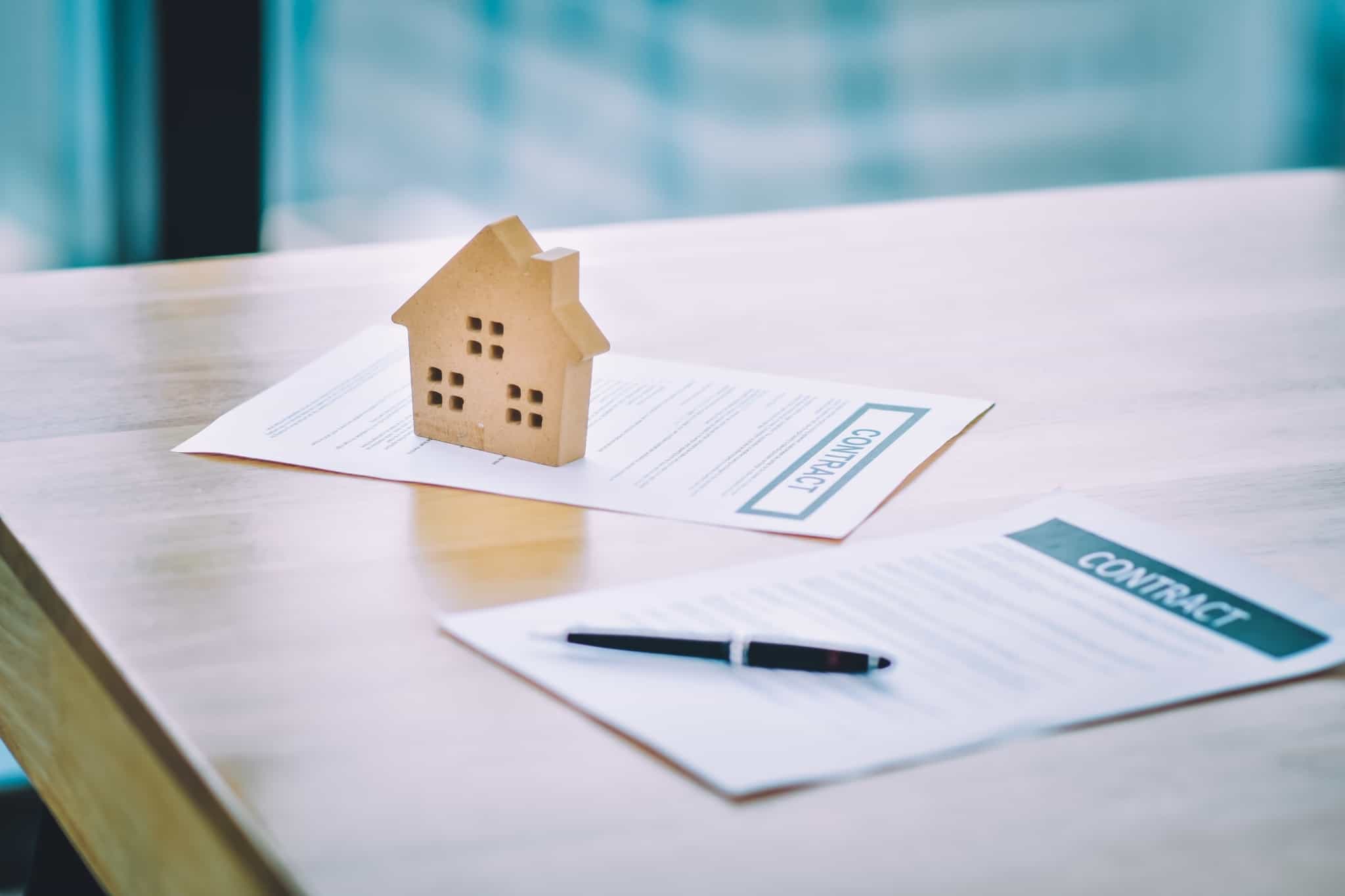 Casa de madeira e papéis de um contrato