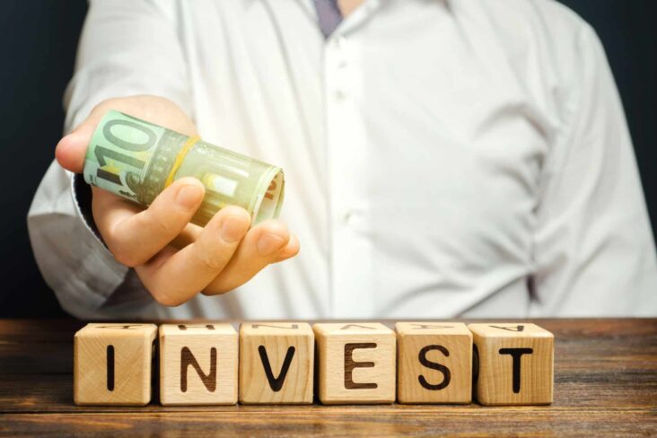 Homem com uma nota de notas na mão e uns dados com letras