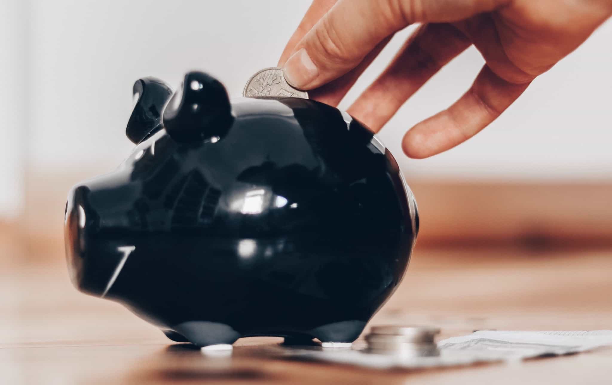 Alguém a colocar uma moeda num porquinho mealheiro