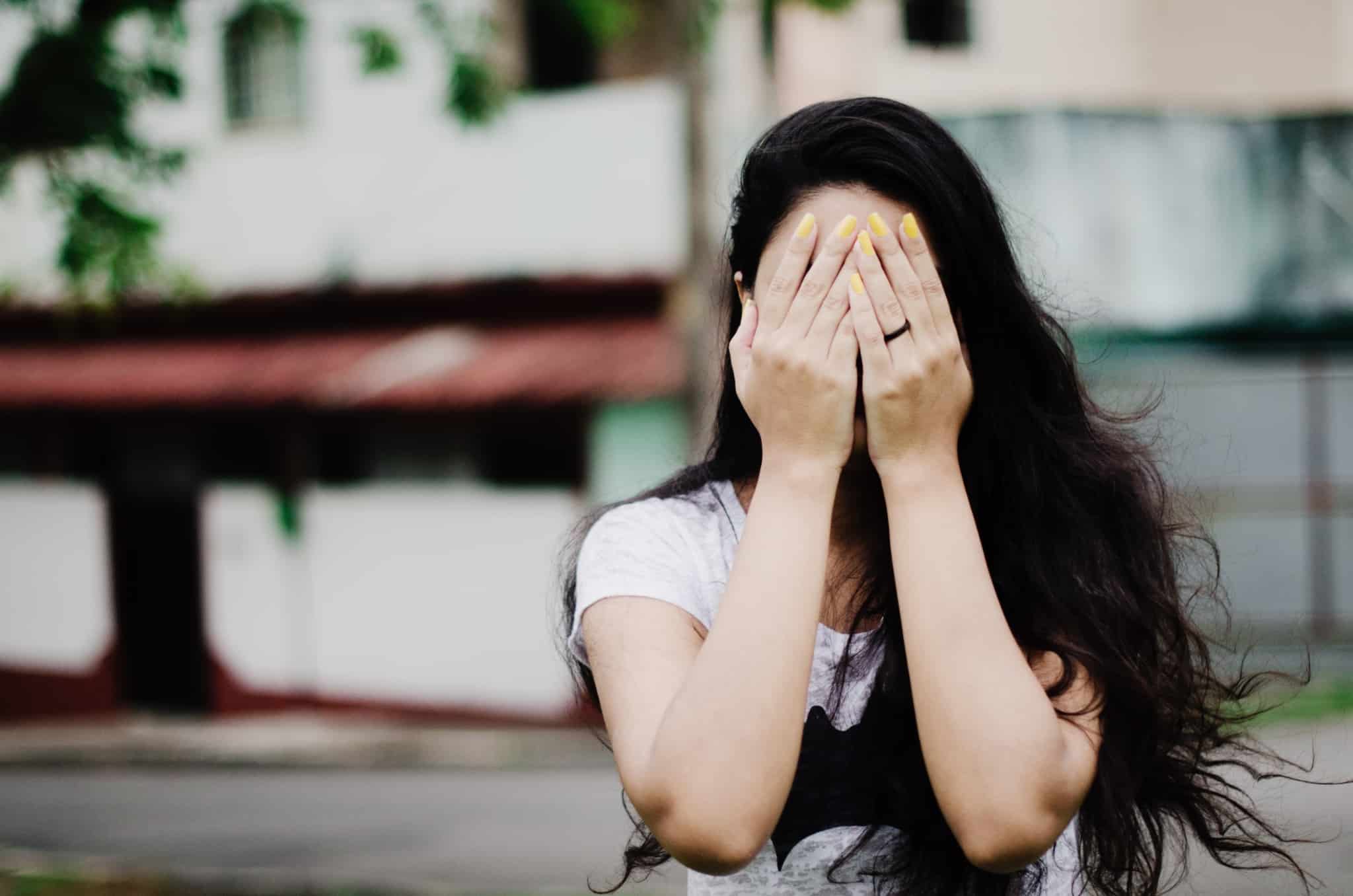 mulher de cabelos negros a tapar os olhos