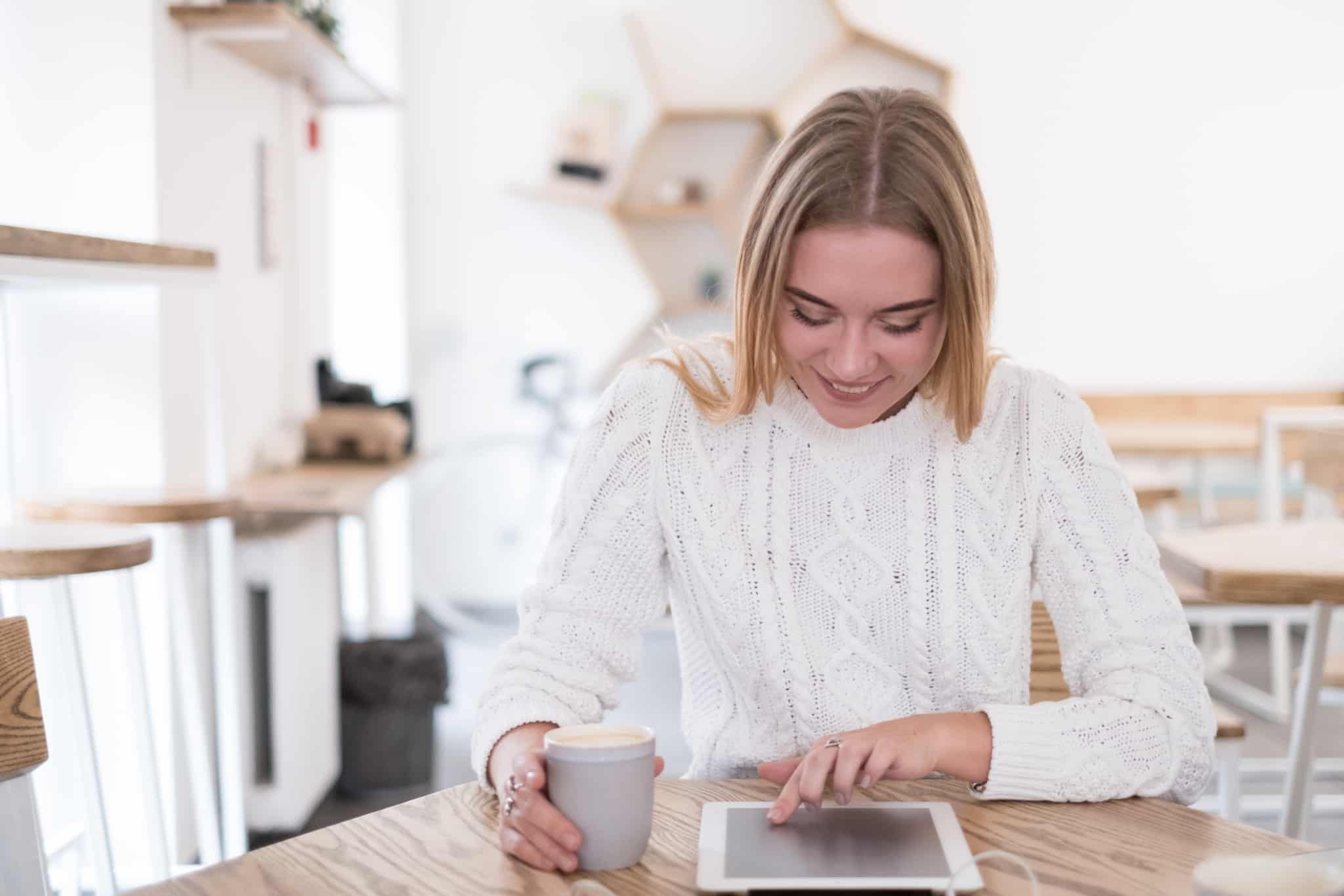 Como poupar dinheiro com o crédito pessoal rapariga a mexer no tablet com uma canela de café na mão