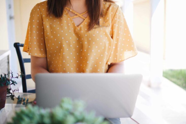 rapariga de blusa amarela a mexer no computador