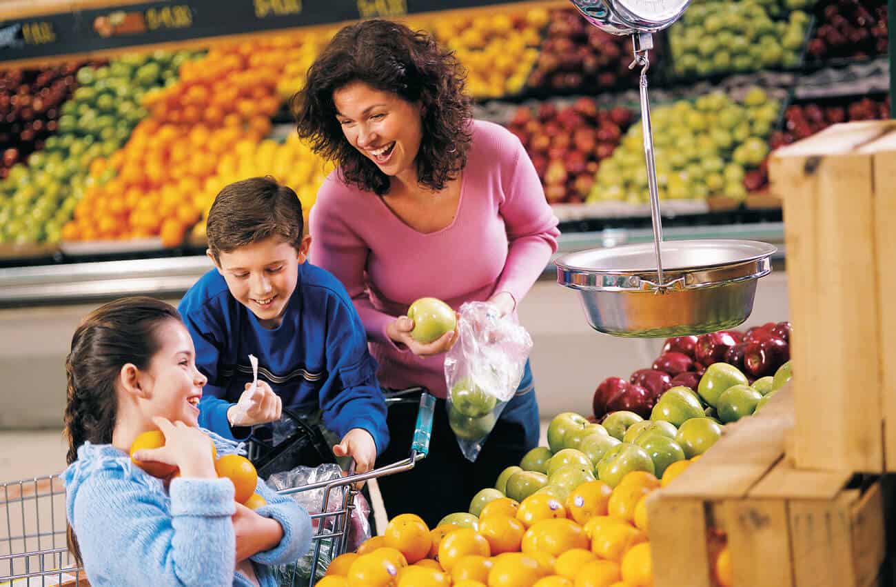 mãe e filhos às compras no supermercado fazem as suas escolhas de fruta e legumes frescos