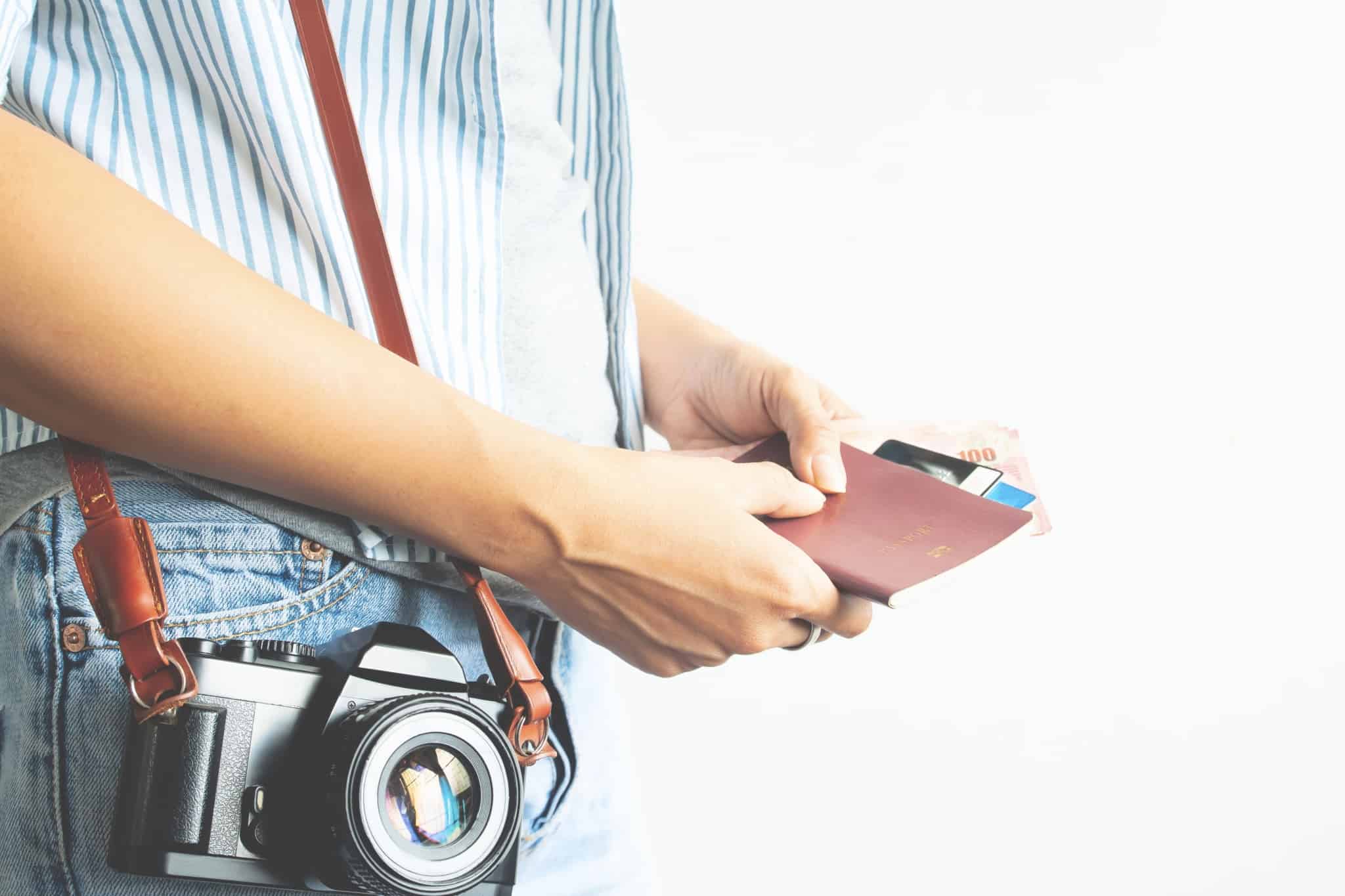 Cartões pré-pagos em viagens para o estrangeiros: como usar? pessoa com maquina fotografica pendurada ao ombro a mexer na carteira com cartões