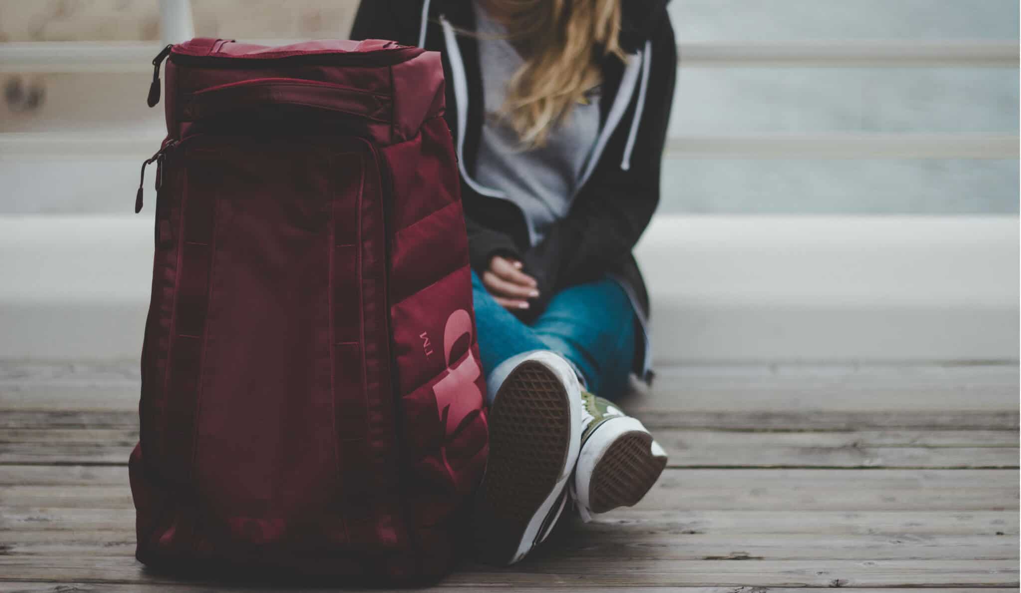 rapariga estudante com uma mochila de viagem vermelha