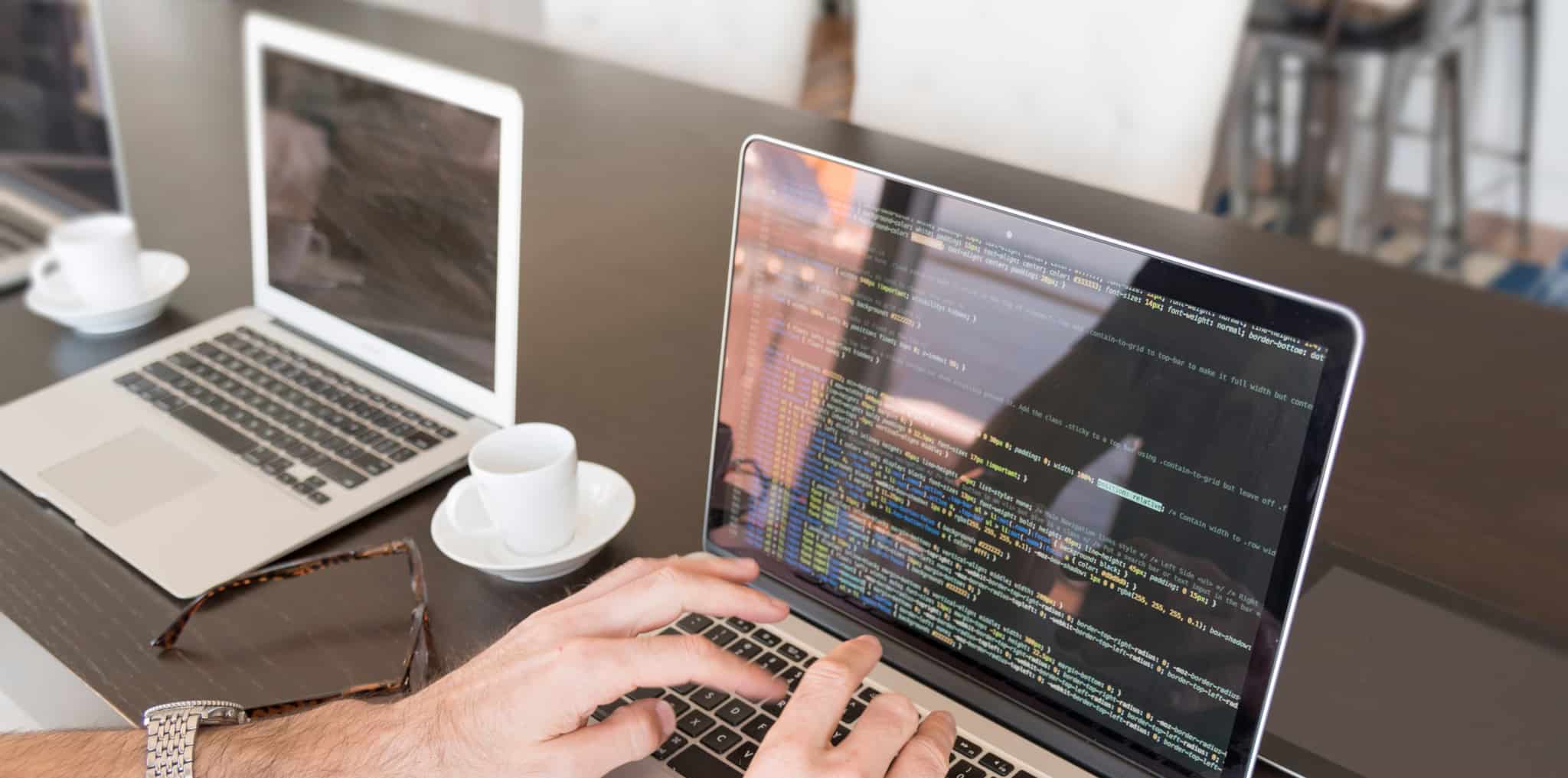 Homem a escrever no computador com chavena de café