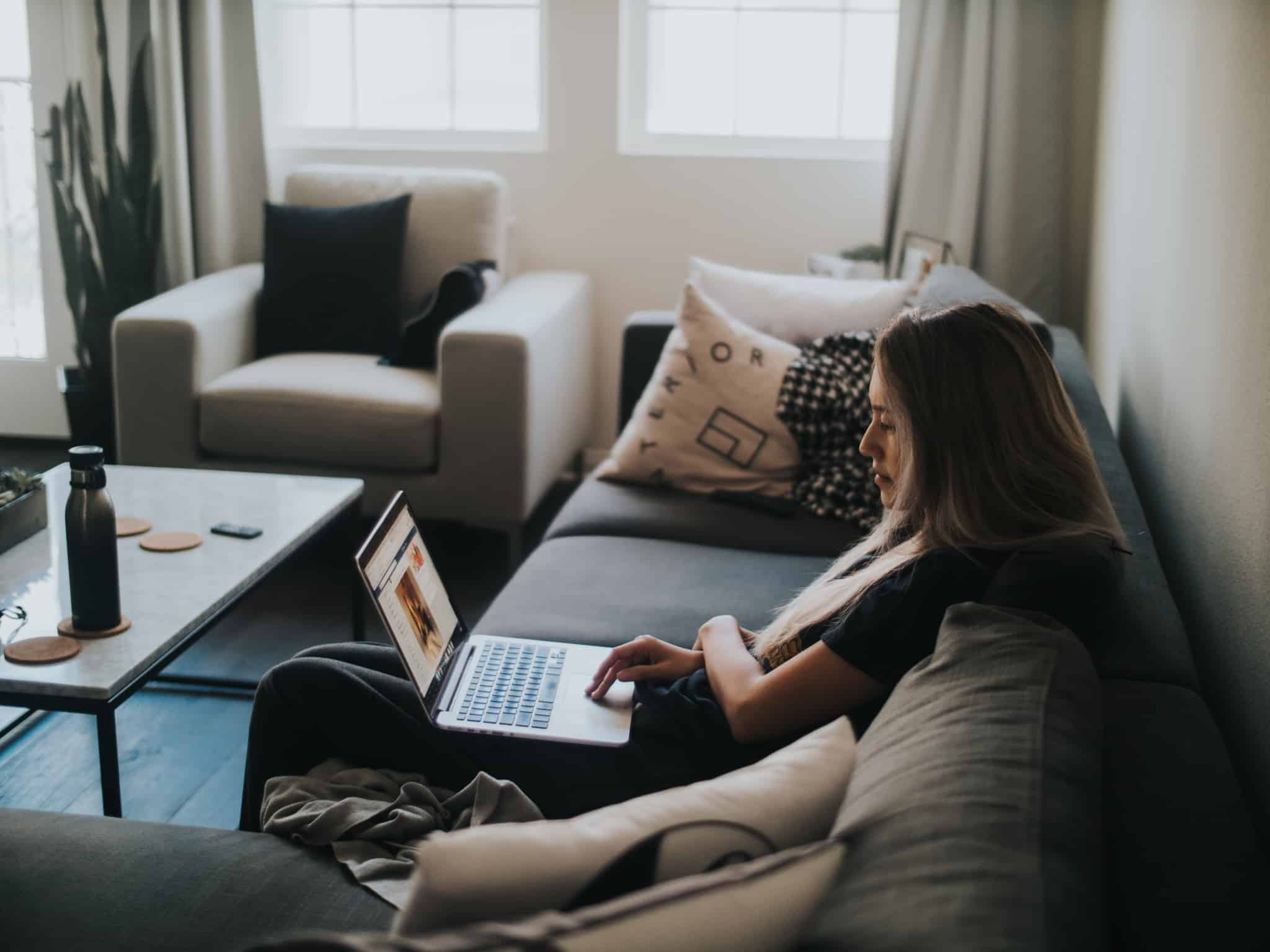rapariga sentada no sofá com computador no colo