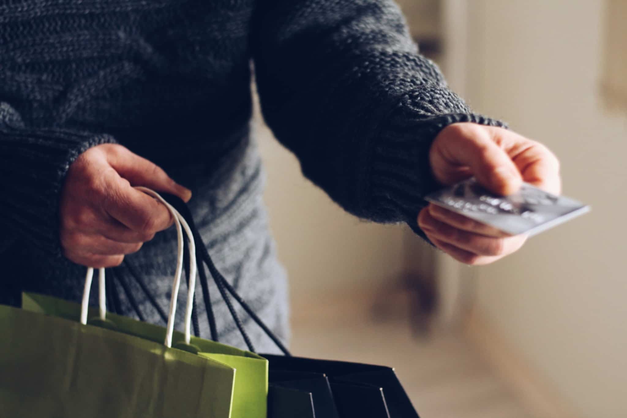 pessoa entrega cartao de pagamentos com sacos de compras