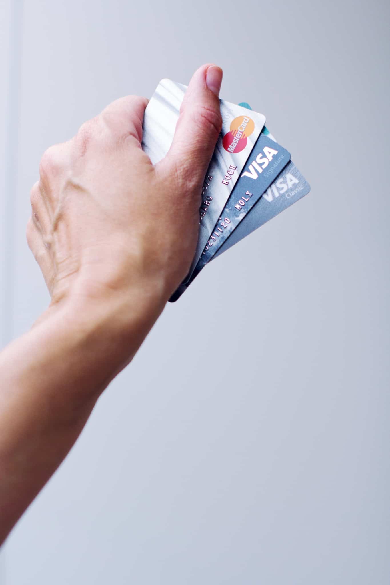 mão a segurar dois cartões visa e um cartão mastercard