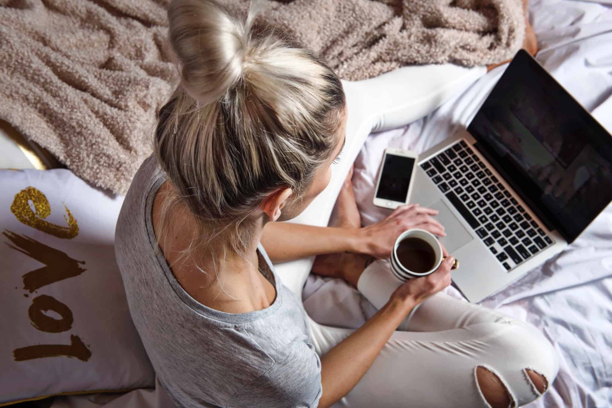rapariga com o portatil em cima da cama