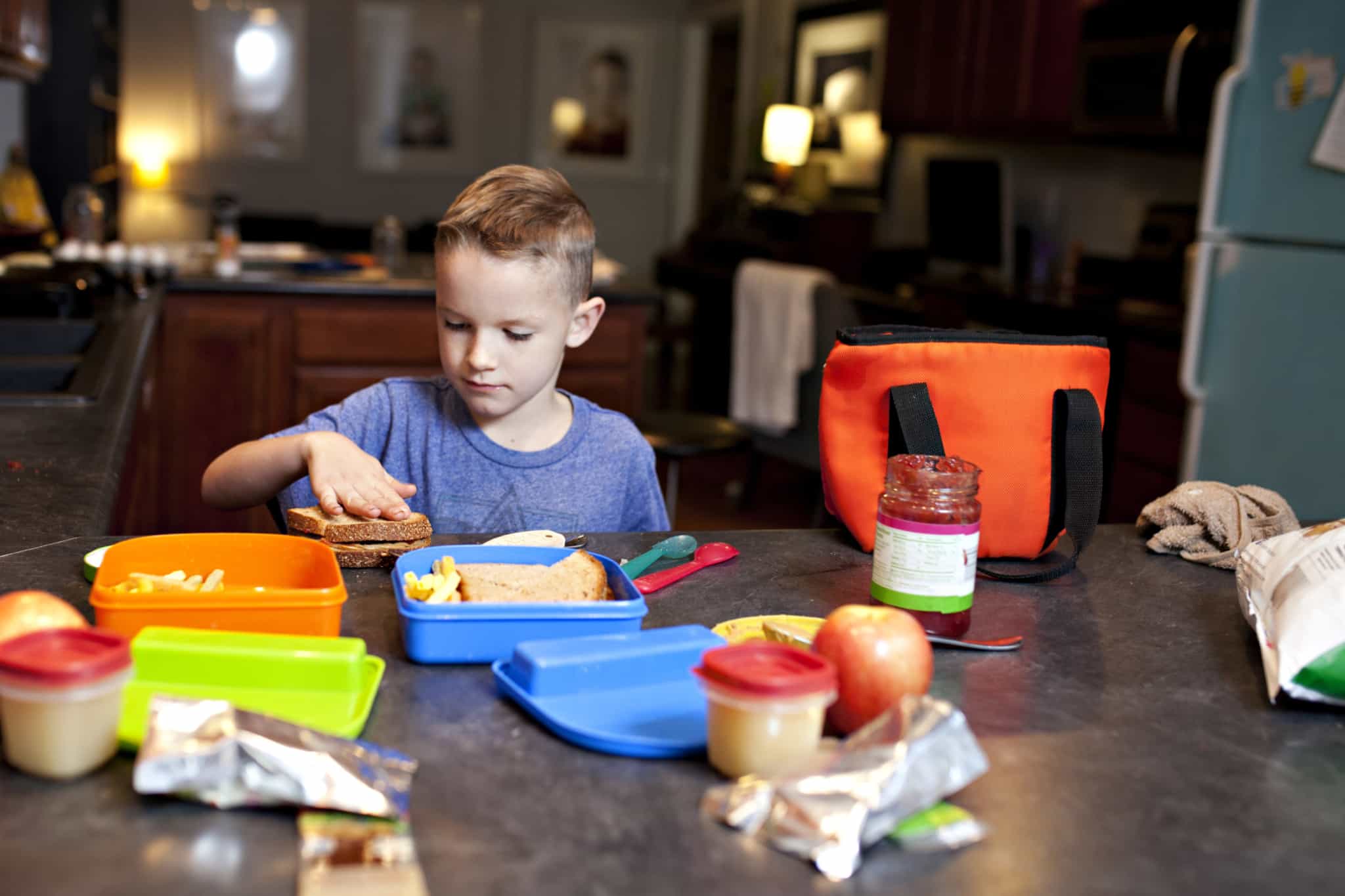 rapaz loiro na cozinha a preparar o seu almoço para a escola