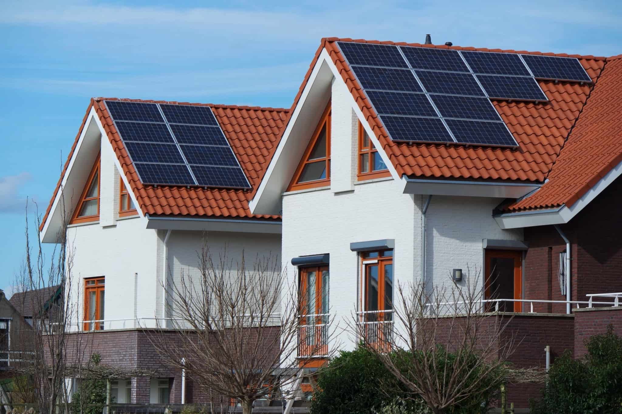 duas casas com telhados triangulares e com painéis solares