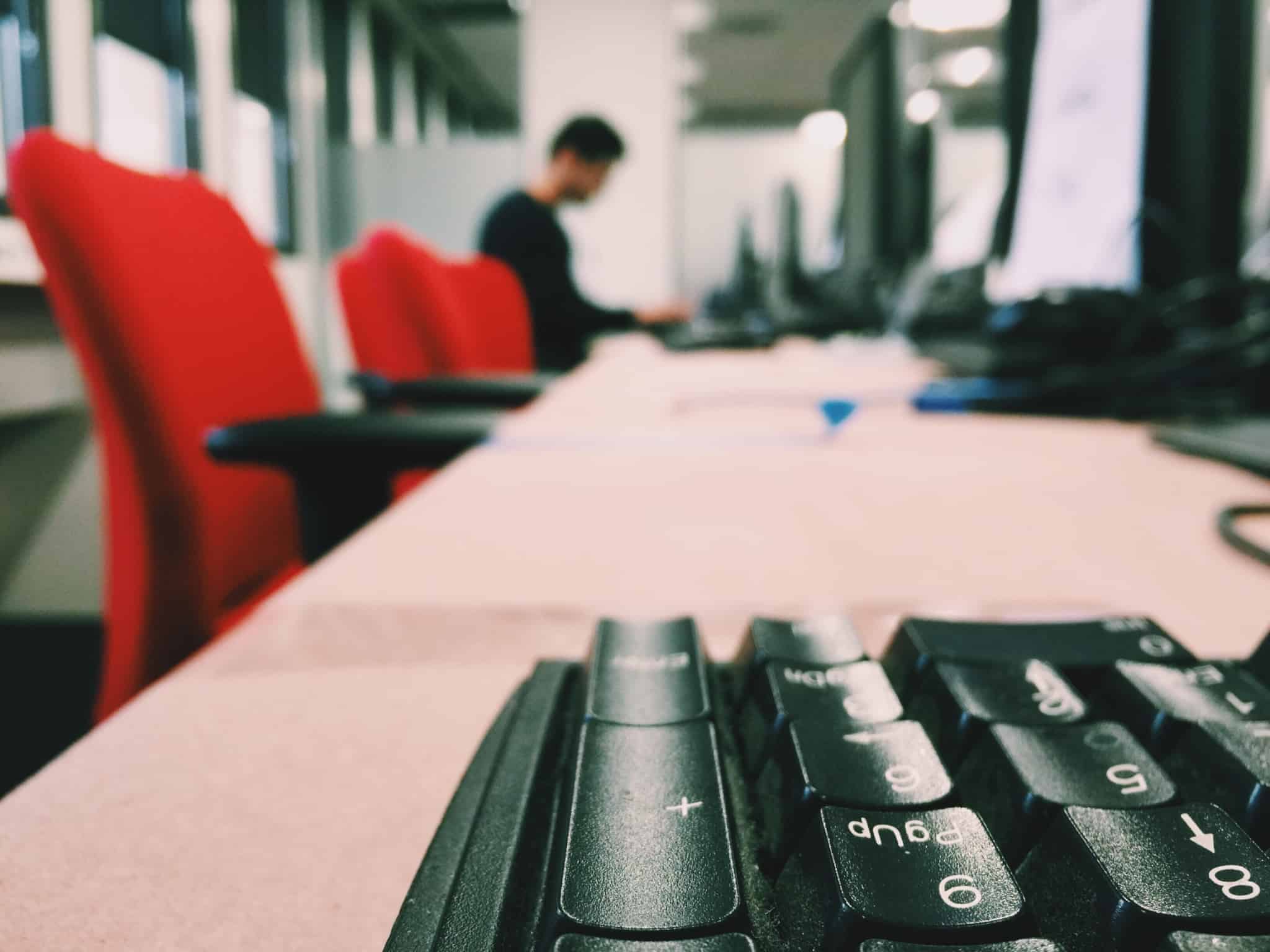 escritório com duas cadeiras vermelhas e um teclado de computador