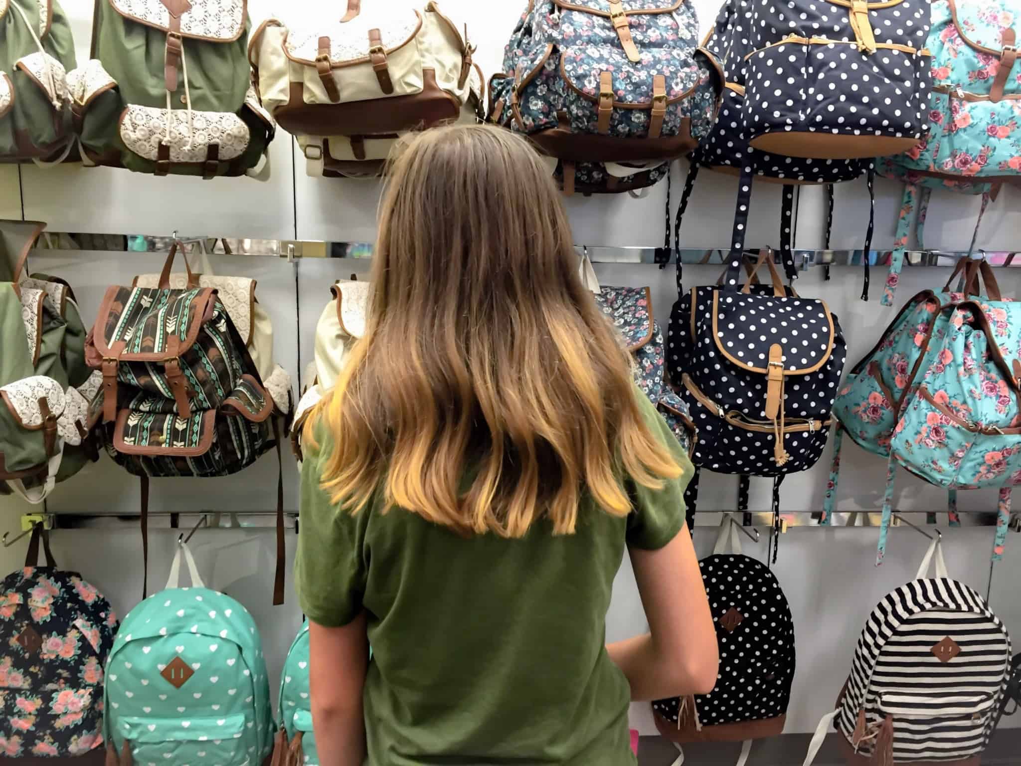 rapariga adolescente a ver malas numa loja