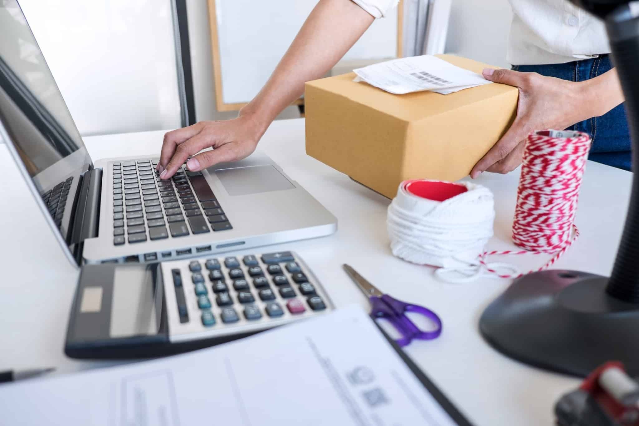 mulher a mexer no computador e a tratar de encomendas da sua loja online