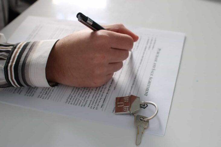 pessoa a assinar um contrato com uma caneta