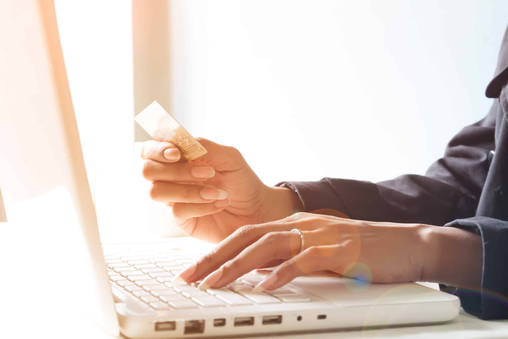 mulher a mexer no computador e a pegar no cartão de crédito