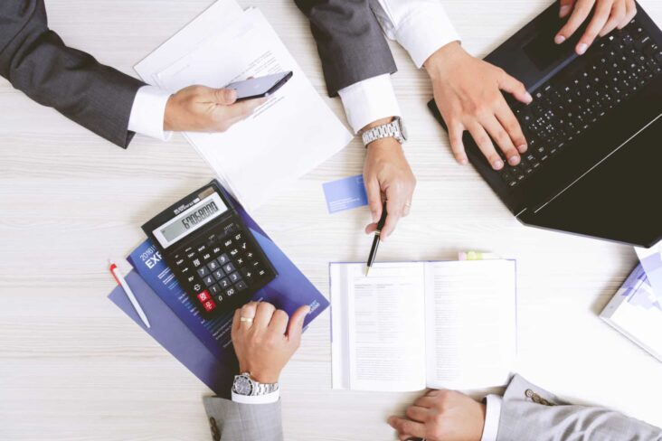 duas pessoas de fato a olhar para números com uma calculadora ao lado