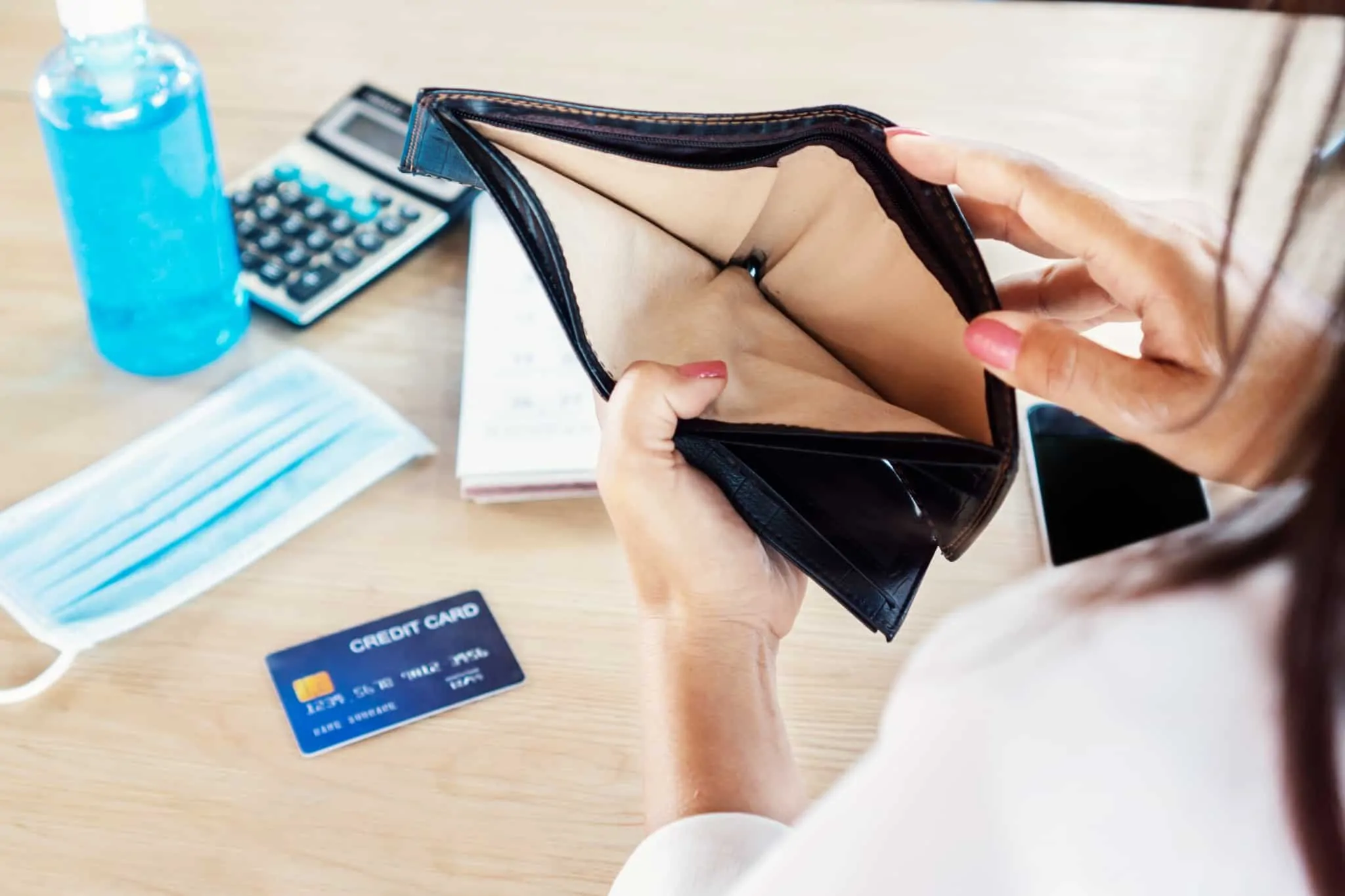 Se a minha situação financeira piorar, o que posso fazer? Mulher com carteira vazia e um cartão de crédito