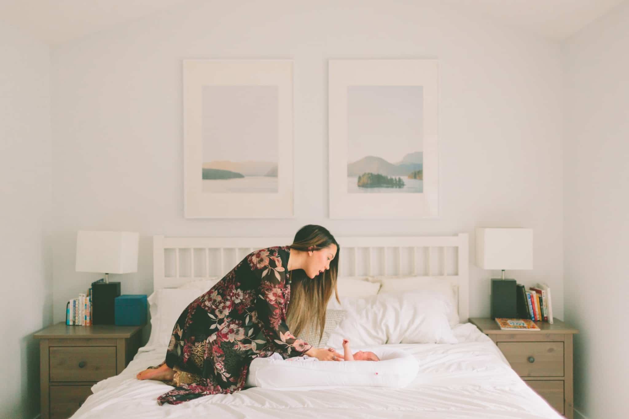 mãe a cuidar do bebé em cima da cama