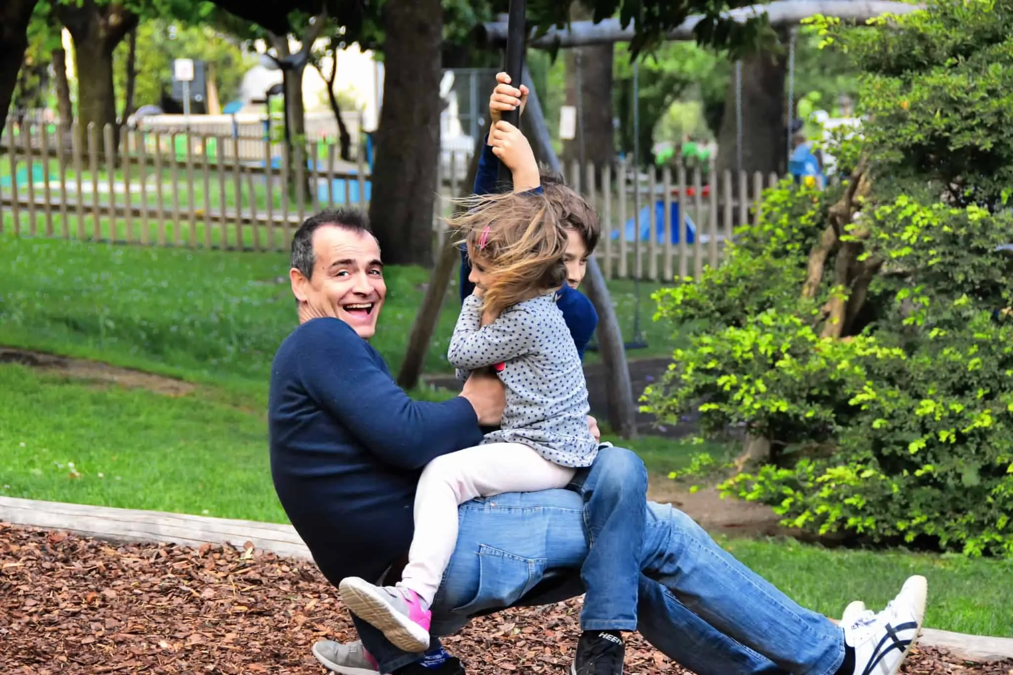 Vai adotar uma criança? Saiba se tem acesso ao subsídio por adoção Pai com dois filhos num baloiço a divertirem-se