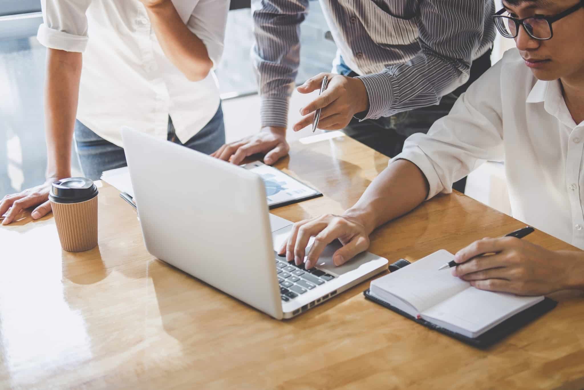 três pessoas a trabalhar em conjunto à frente de um computador