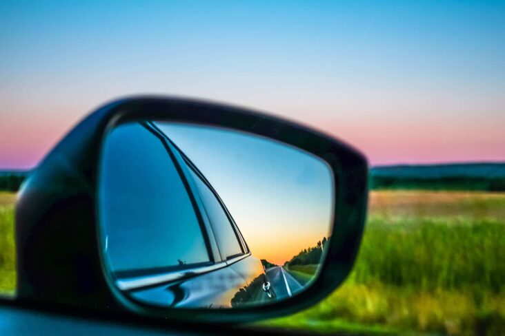 Retrovisor de um carro onde se vê um campo verde