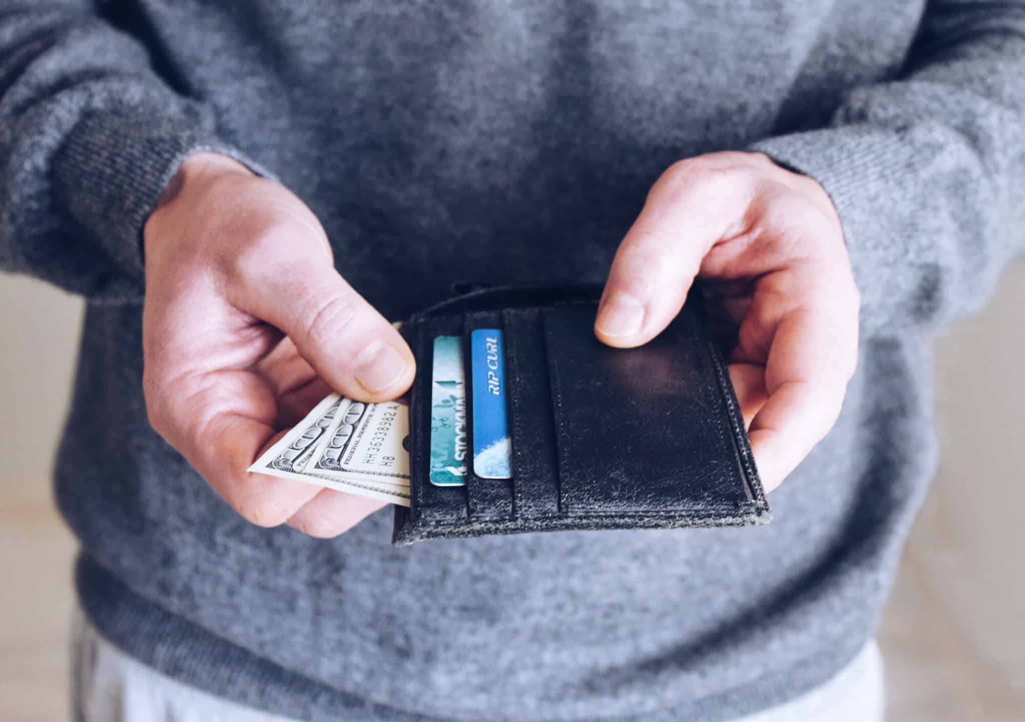 pessoa a mexer na carteira com cartões e notas