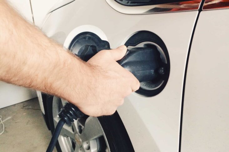 Mão de um homem a pôr o carro elétrico a carregar