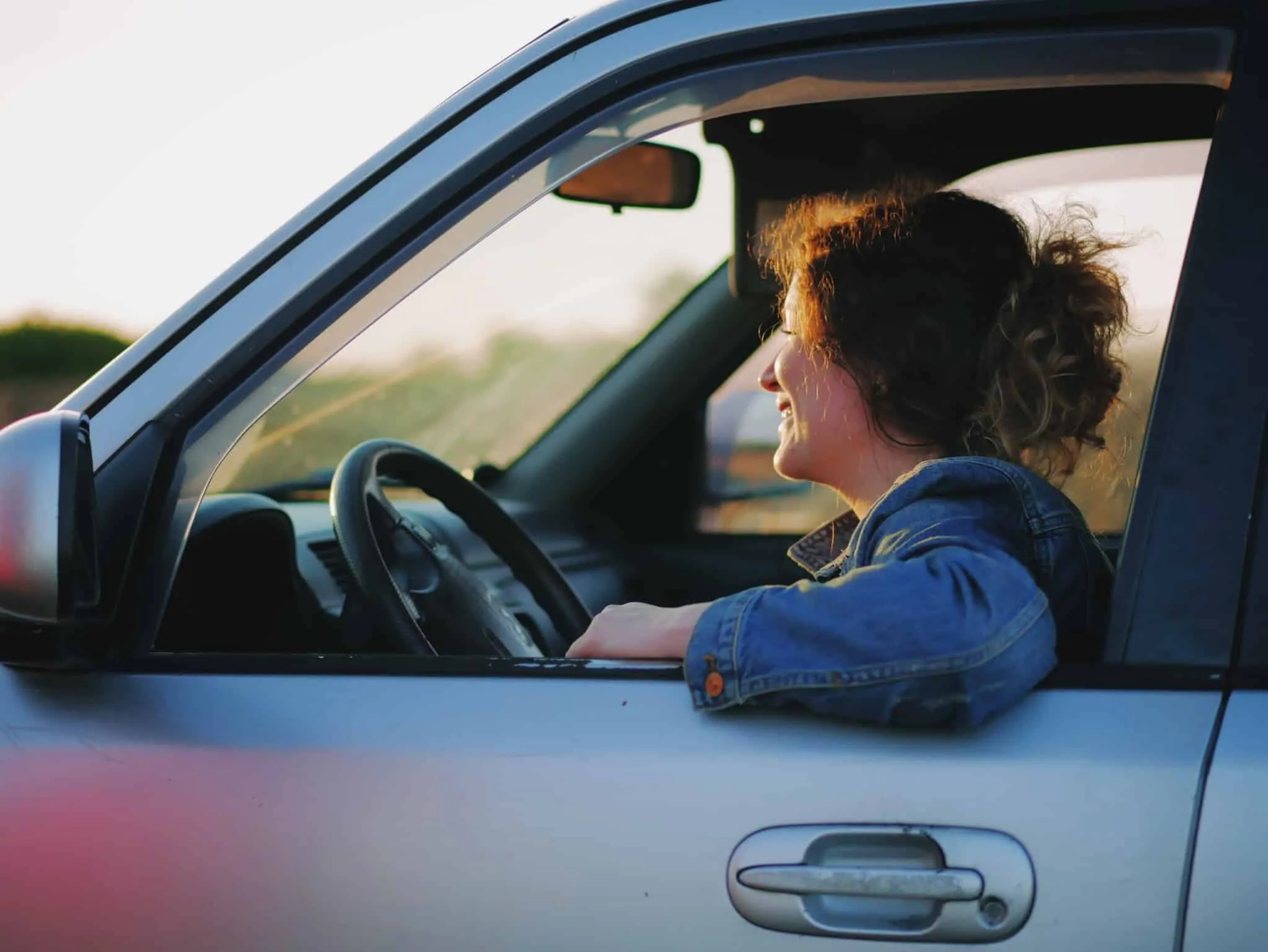 Agravamento do seguro automóvel: 5 fatores para não conseguir pagar menos de seguro mulher condutora a sorrir