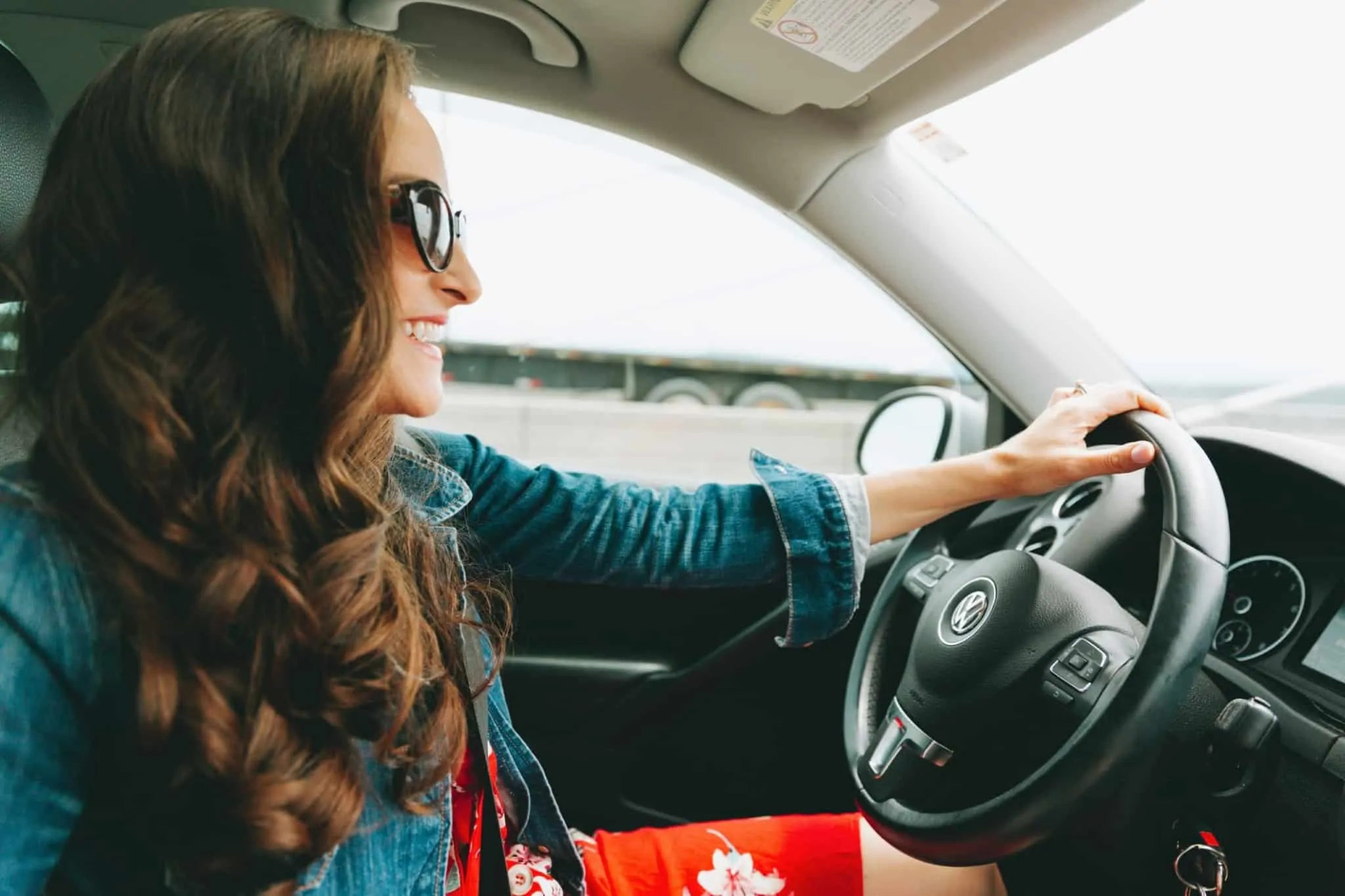 senhora morena sorridente a conduzir um carro
