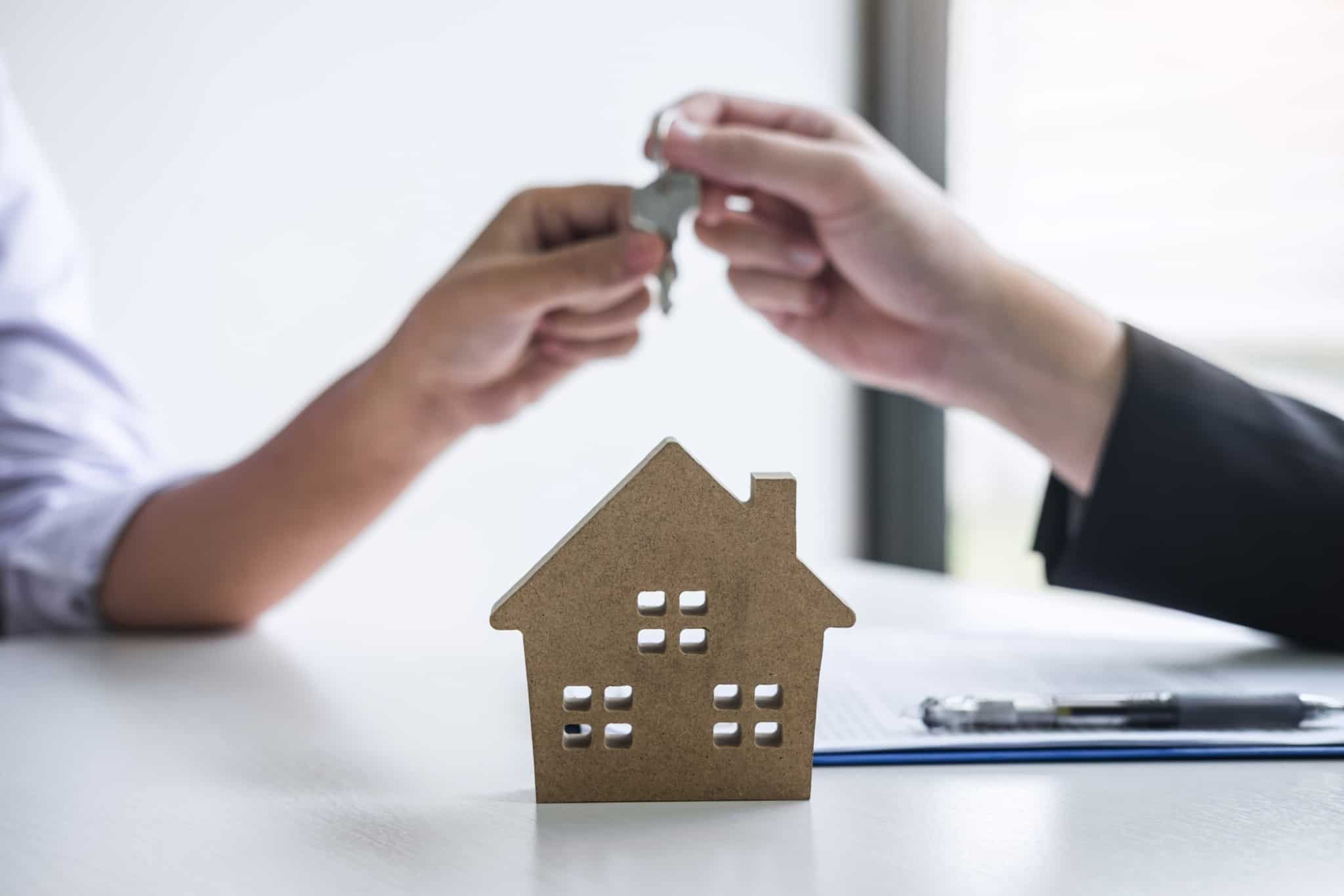 agente imobiliário a dar chave de casa a um cliente com camisa branca