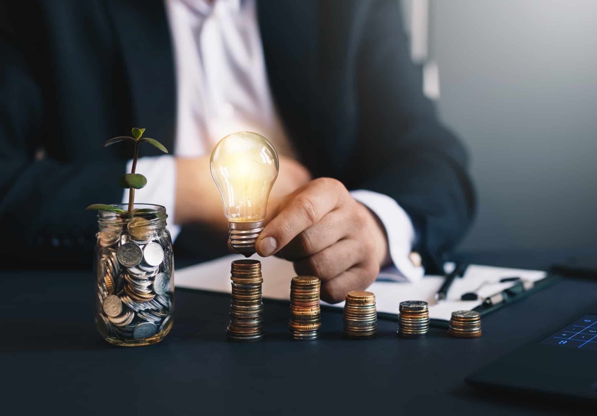 7 formas de poupar na conta da luz este inverno Montinhos de moedas poupadas e lâmpada