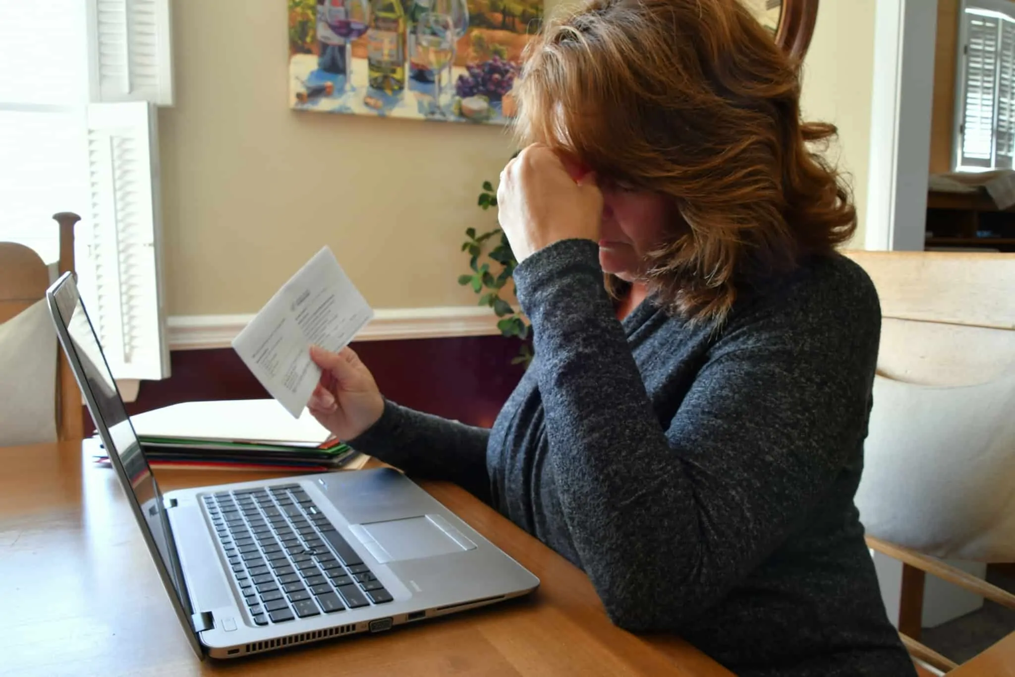 Insolvência pessoal: vantagens e desvantagens mulher com ar preocupado em frente ao computador, com uma carta numa mão