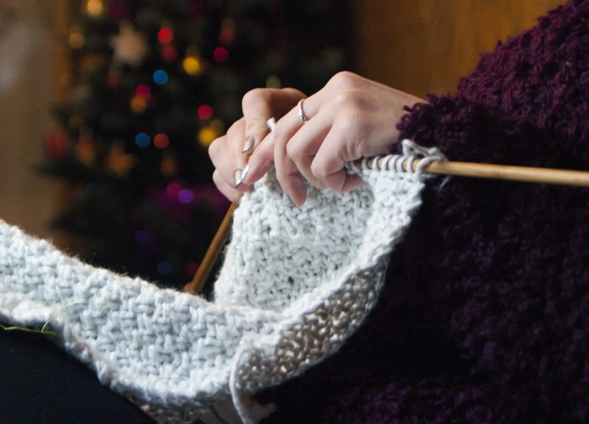 Precisa de um rendimento extra no Natal? 7 opções que pode ponderar mulher faz tricô ao pé de uma árvore de Natal