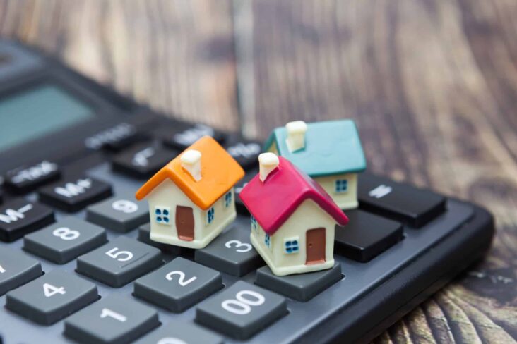 figuras de casas em miniatura em cima de uma máquina de calcular