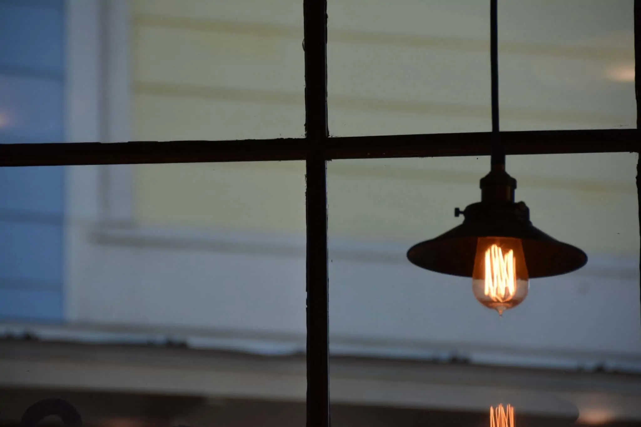 Saiba como escolher o melhor fornecedor de eletricidade Imagem de um cadeeiro de teto dentro de uma casa. Como pano de fundo está uma janela com com vista para a casa da frente