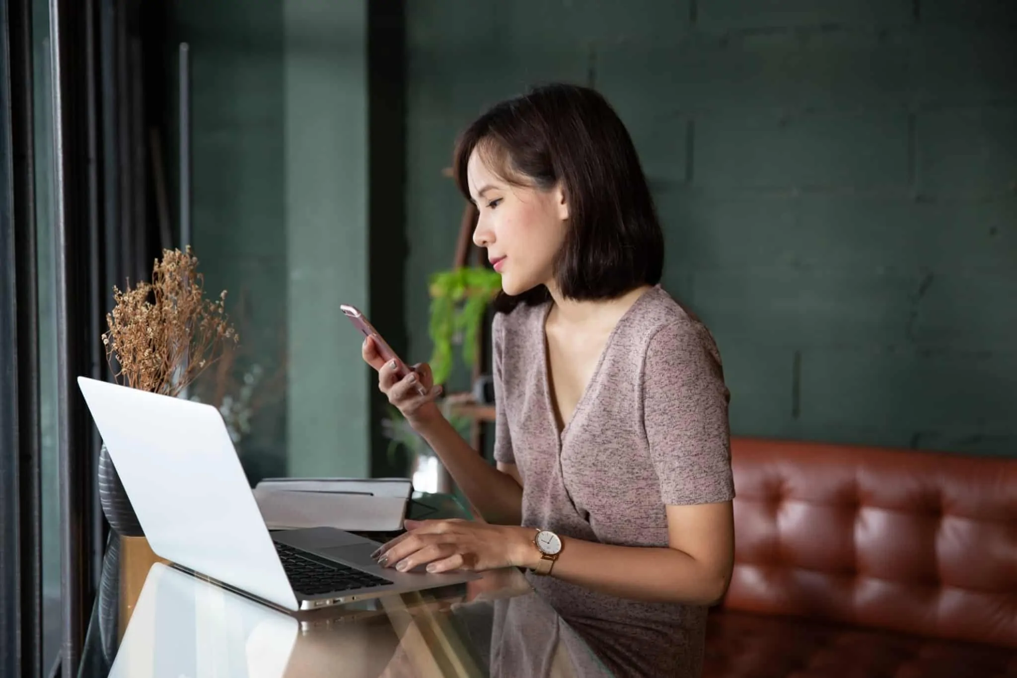Entrevista de emprego online: Que cuidados deve ter e como transmitir o seu potencial Mulher em frente ao computador e como telemóvel na mão