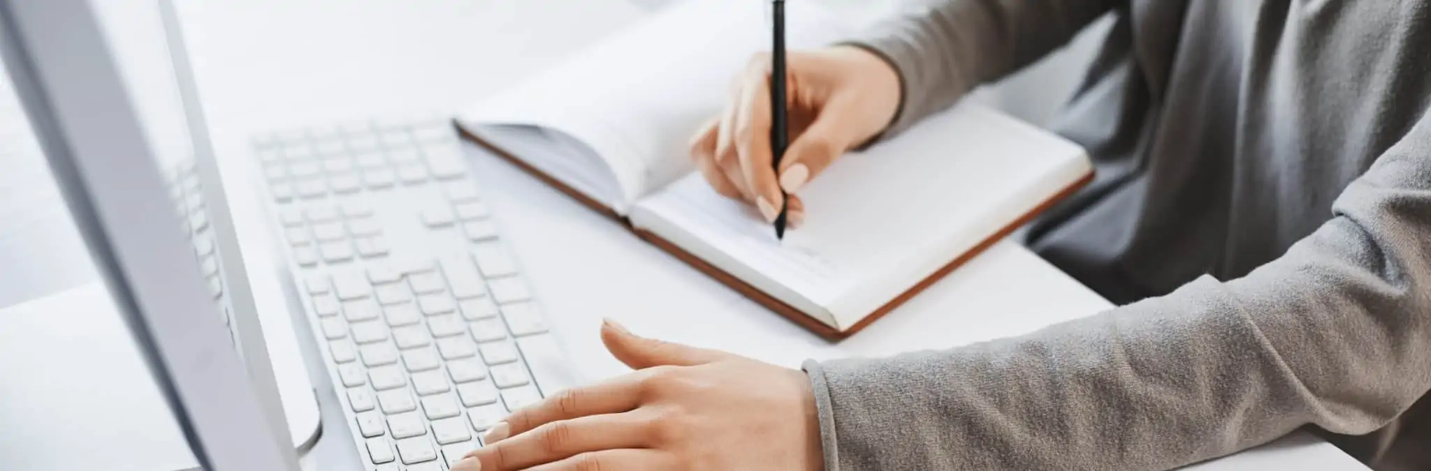 Vou mudar de emprego. O que devo ter em consideração? mãos femininas a escrever no teclado e caderno