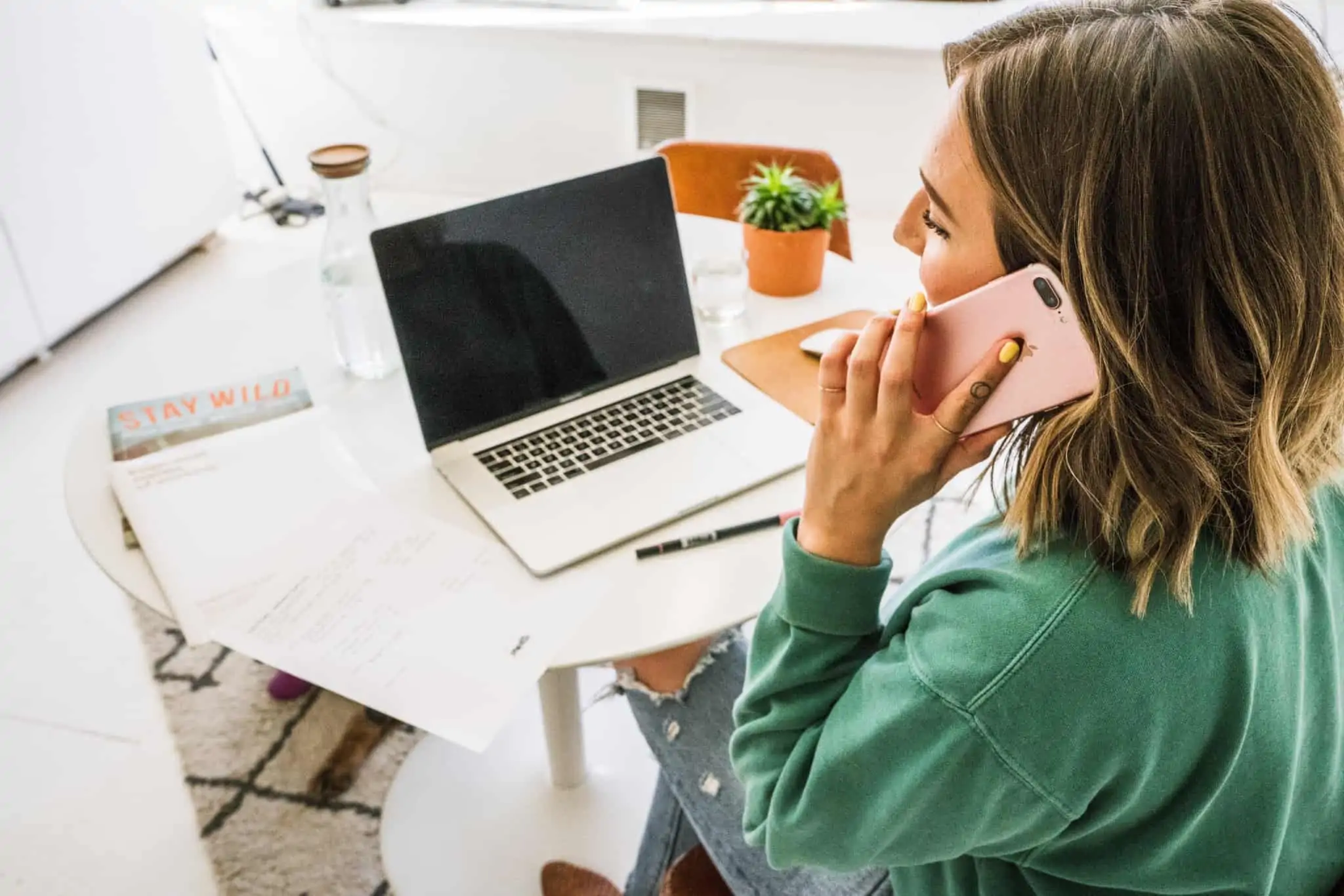 Apoio extraordinário ao rendimento dos trabalhadores: quem tem direito a este novo apoio? Mulher fala ao telemóvel, enquanto trabalha em casa