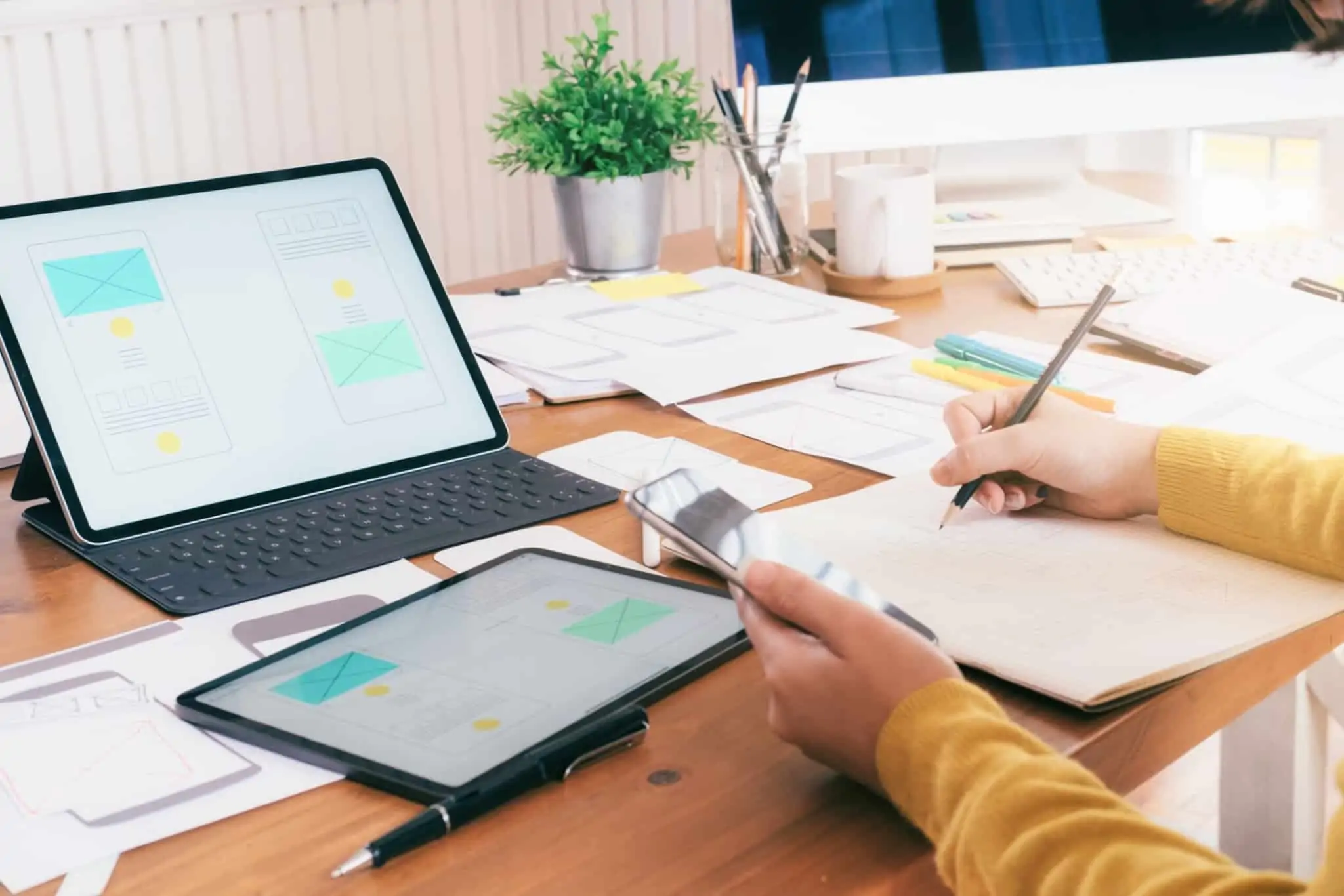 Como calcular o IRS de trabalhadores independentes em 2023 Pessoa numa mesa de trabalho, com um computador, um tablet e blocos de folhas em cima da mesa, ilustrando como calcular o IRS de trabalhadores independentes em 2023