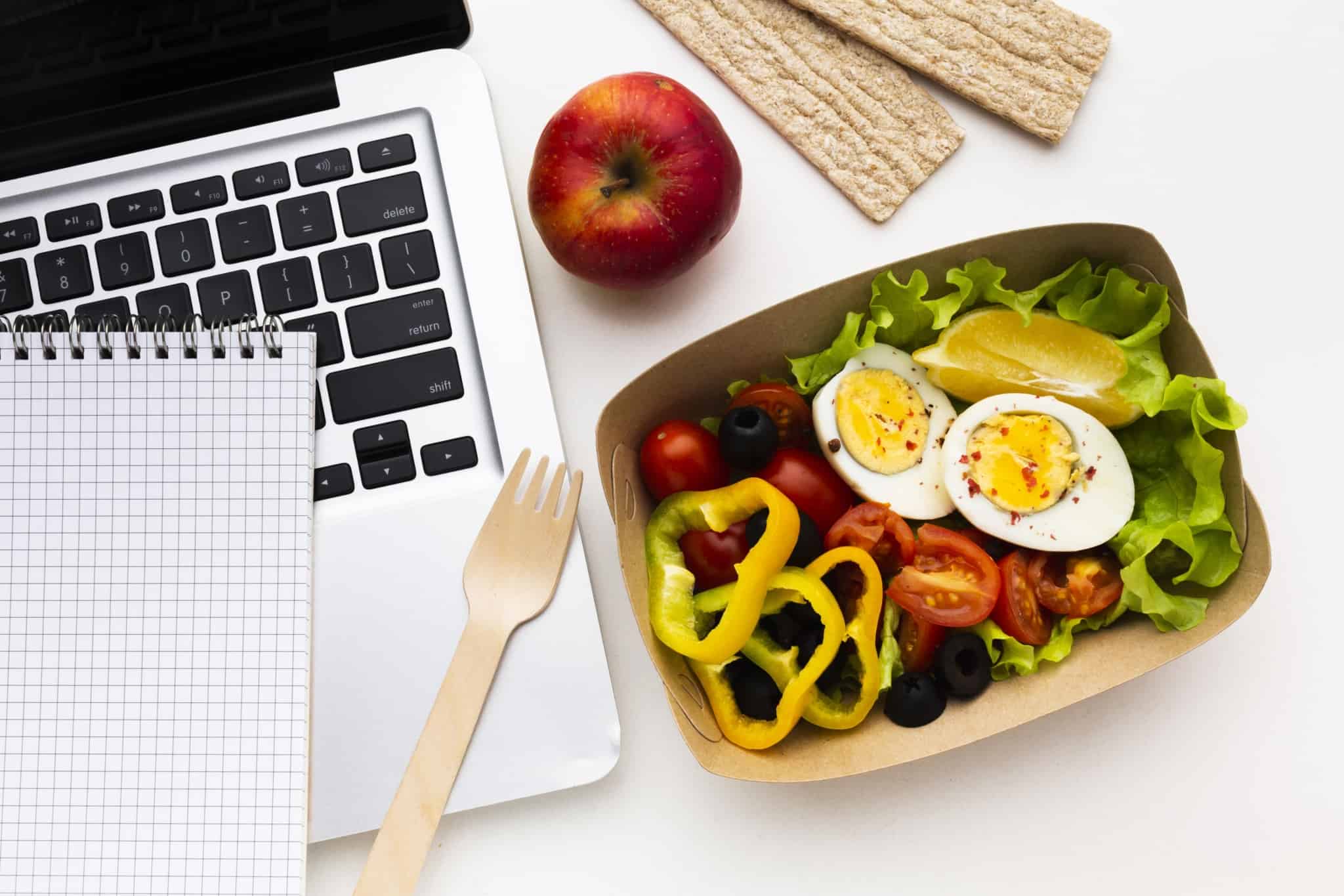 7 cuidados a ter com compras em supermercados on-line uma embalhagem com uma salada composta por vegetais e ovos ao lado de um computador