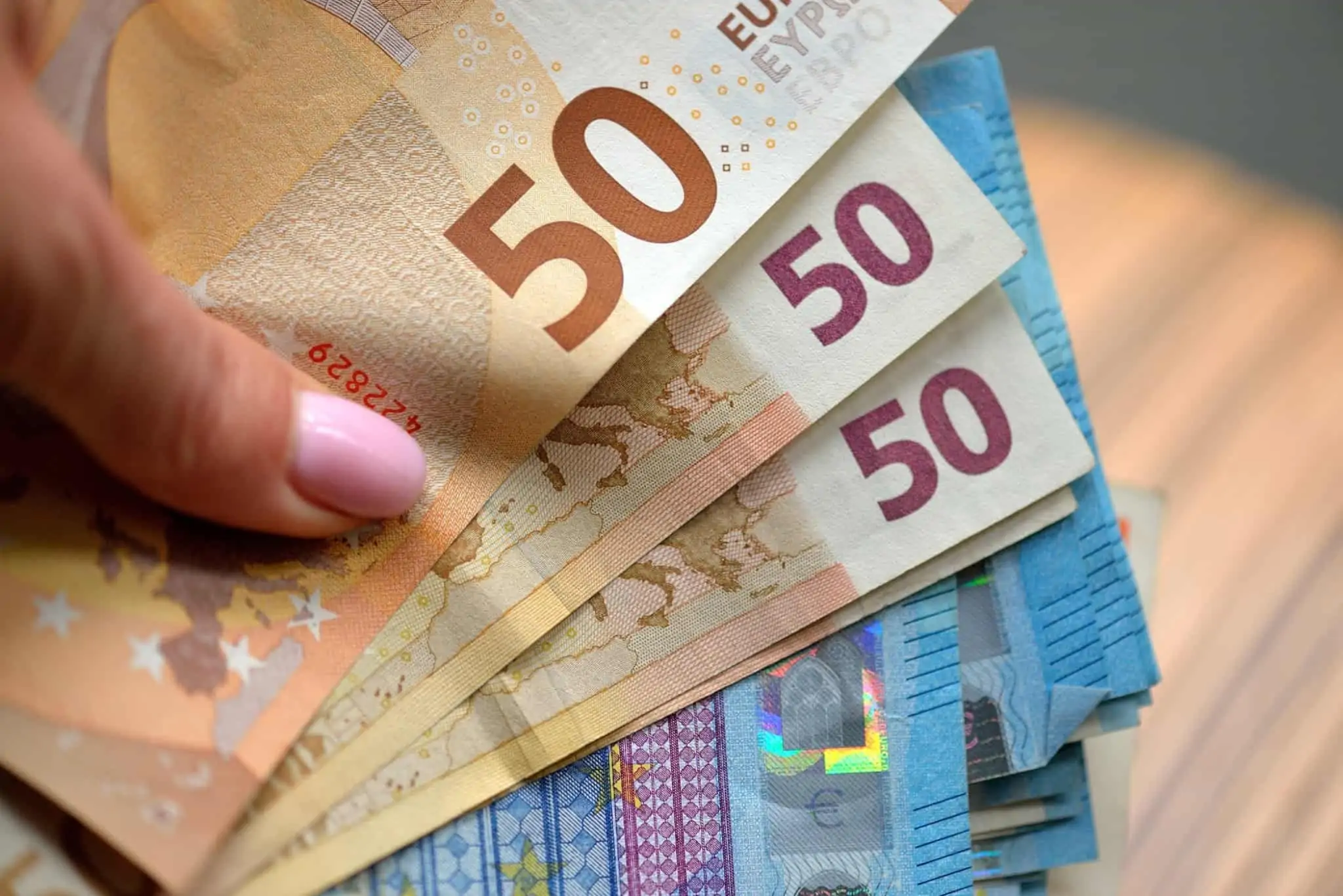 Mão de mulher com várias notas de 50 e 20 euros