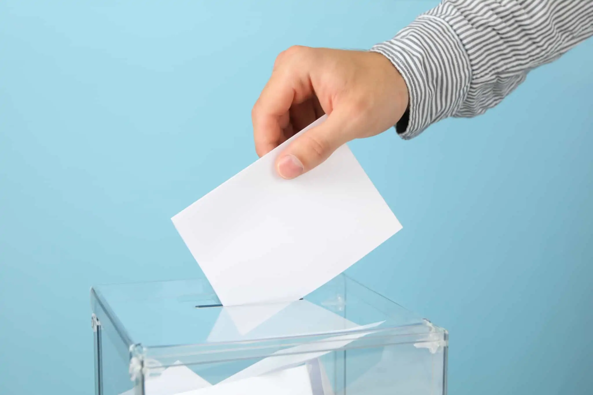 Direito de voto: Quais são os seus direitos e como votar antecipadamente Homem coloca o seu voto numa urna de voto