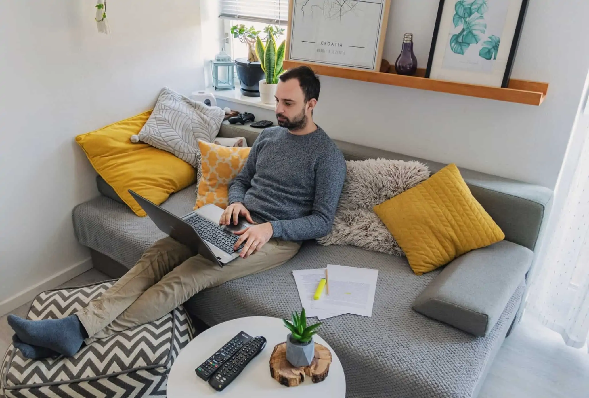 Modelo 1 do IMI: como preencher para pedir reavaliação do imóvel Homem sentado no sofá a trabalhar com o seu portátil em cima das pernas
