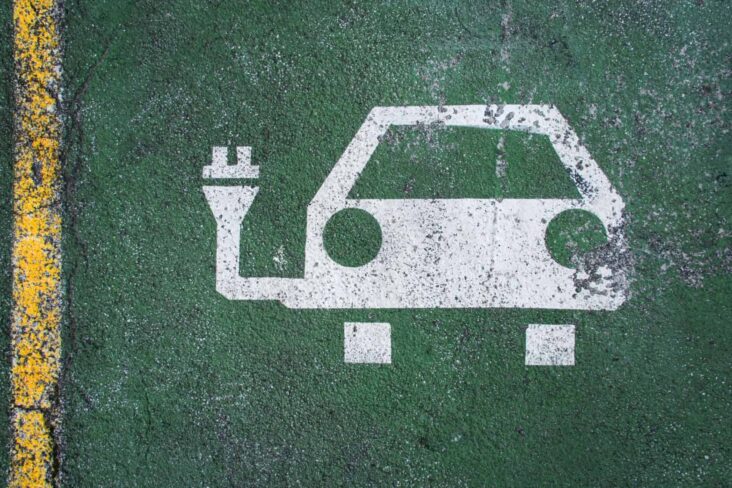 Desenho de um carro ligado a uma ficha elétrica pintado no chão a identificar uma zona de carregamentos de carros elétricos