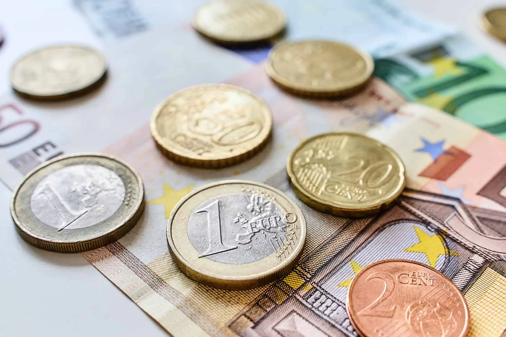 Declarar mais-valias no IRS: que anexo deve preencher? moedas de euro em cima de algumas notas de euro