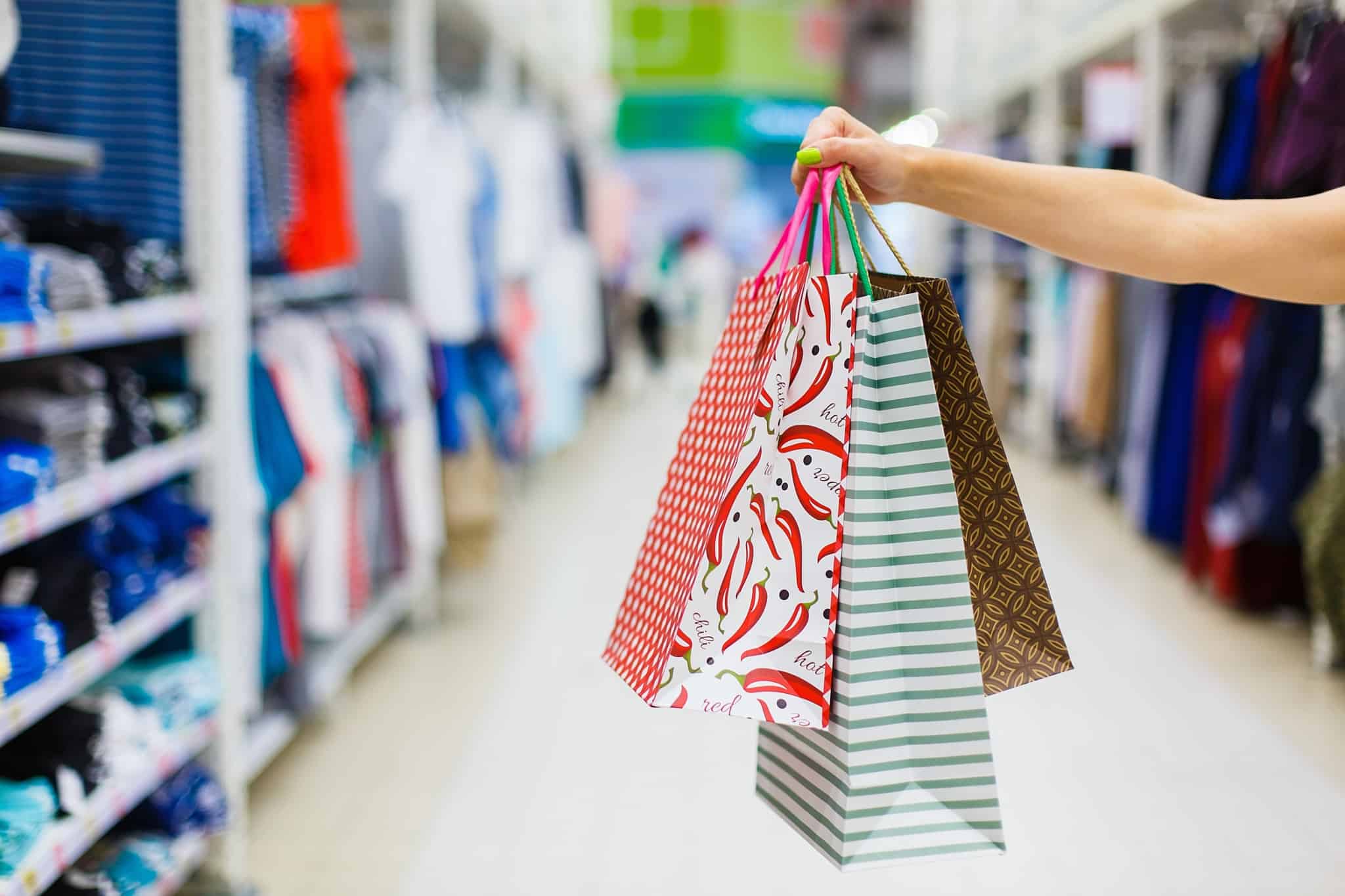 Preço e valor: O que realmente importa na hora de ir às compras uma mão com três sacos de compras de papel coloridos