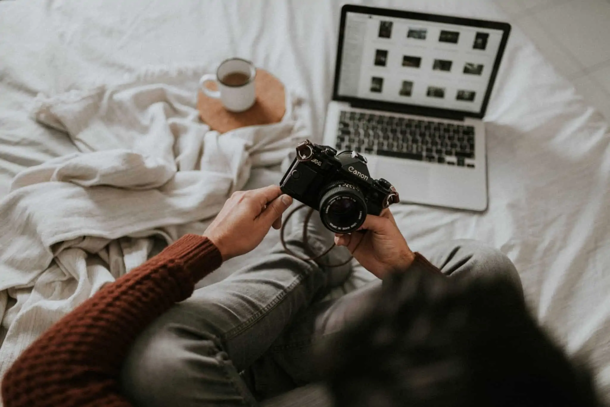 8 sites de imagens gratuitas Pessoa com uma máquina fotográfica na mão. Á frente tem um computador, onde descarregou fotografias