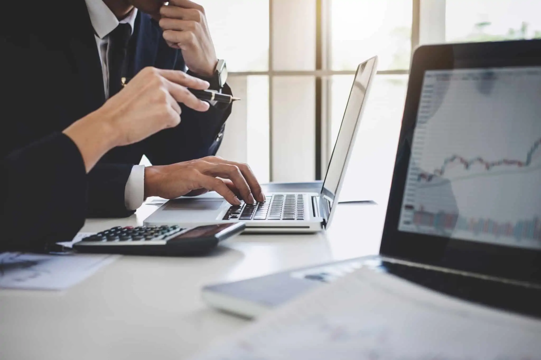 O que são e como funcionam as obrigações? dois colegas de trabalho analisam dados num computador